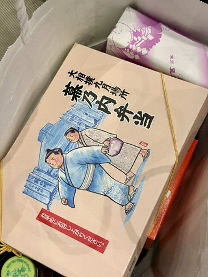 紙袋の中に入った、蓋に力士のイラストが描かれた幕の内弁当