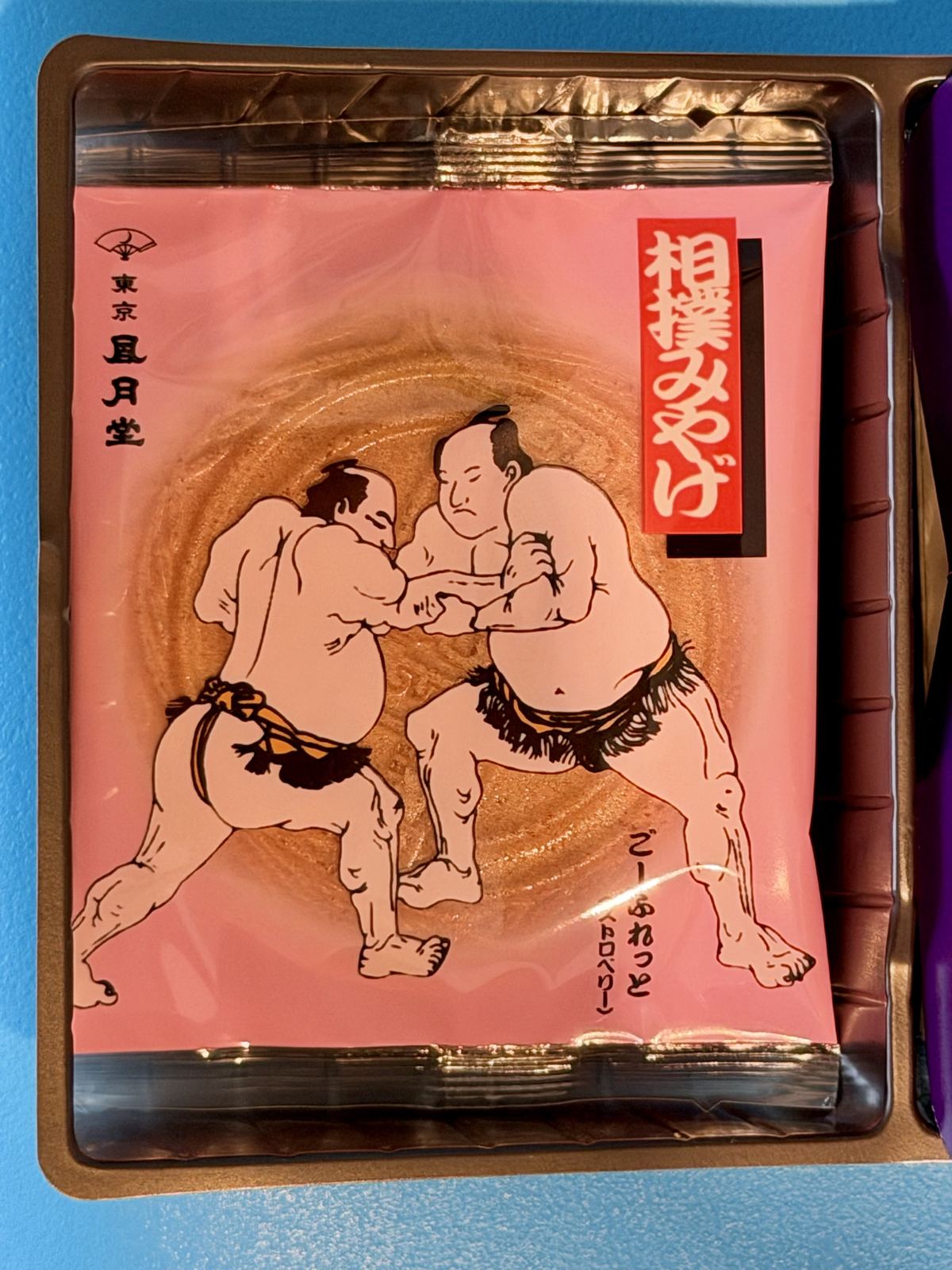 錦絵風の力士二人と「相撲みやげ」の文字が入った、ごーふれっとの桃色の包み