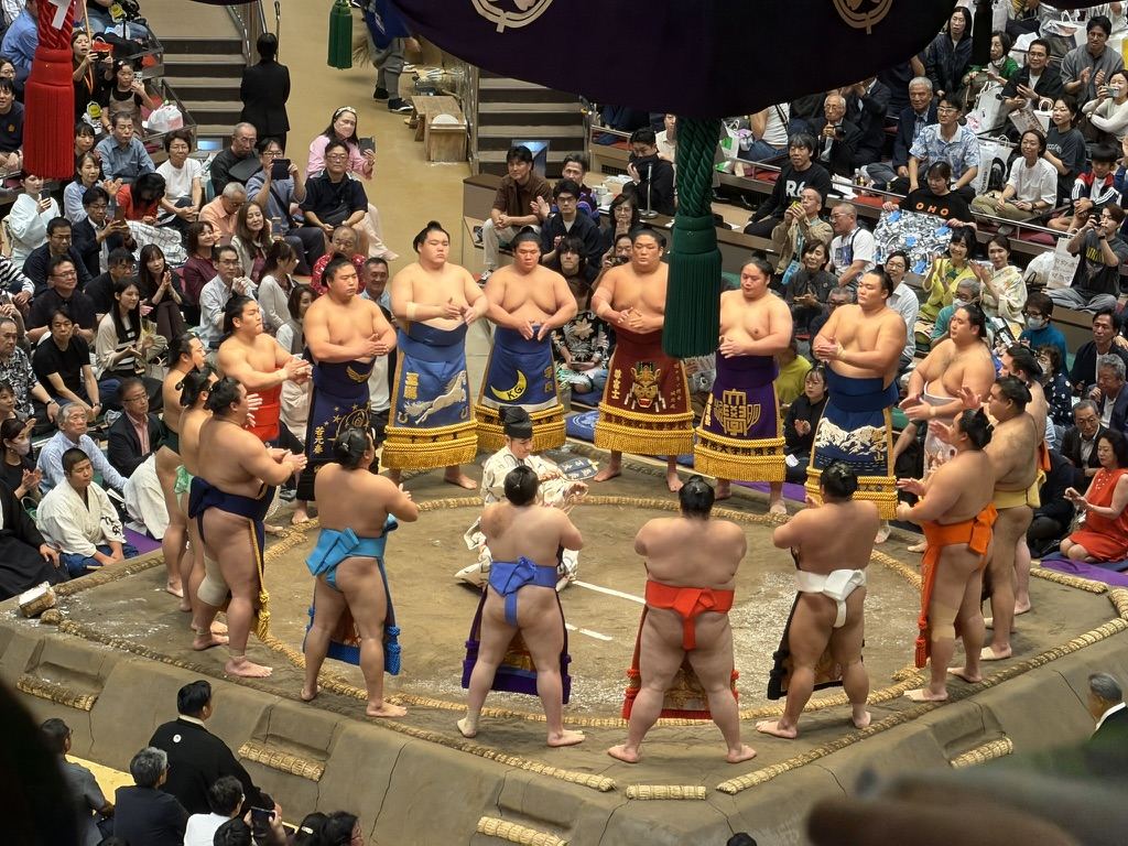 化粧廻し姿の幕内力士たちが、土俵の上で円になっている