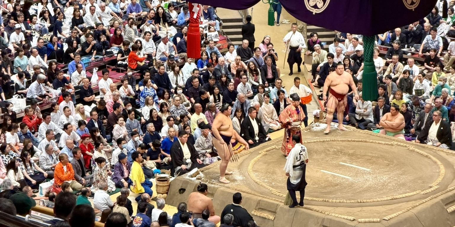 The sumo ring at Ryogoku Kokugikan under its hanging roof, seen from the second floor with the hall full
